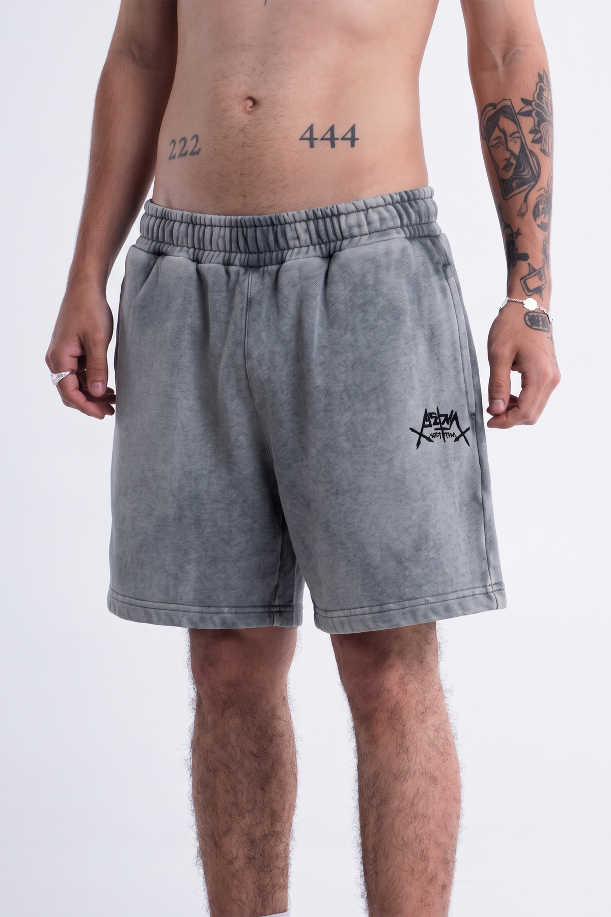 Modelo veste o Aspalth Shorts cinza, vista frontal do quadril aos joelhos
