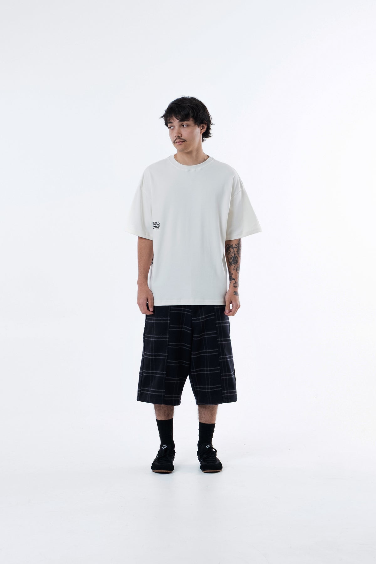 Modelo veste a Hypnotist Heavy Tee off-white com bermuda xadrez, vista frontal de corpo inteiro