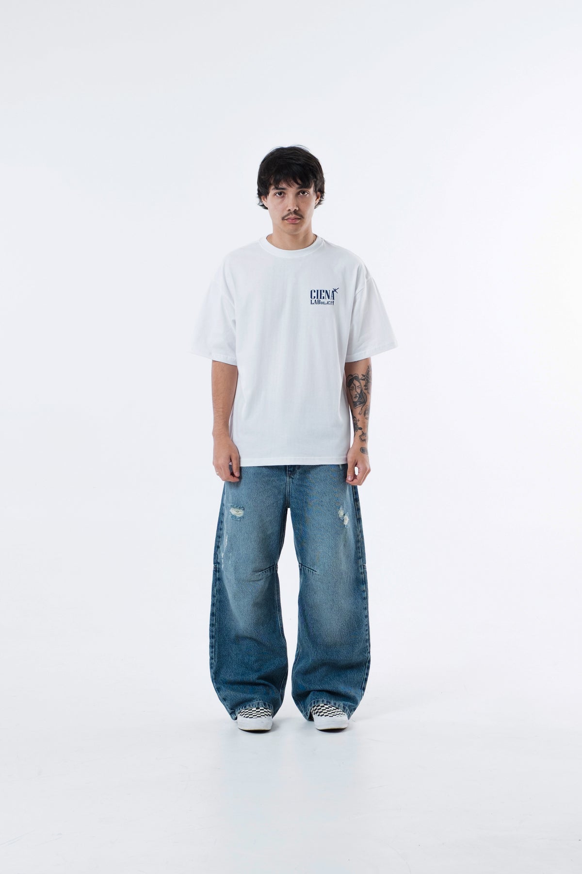 Modelo veste a A Danca Classic Tee off-white com calca jeans, vista frontal de corpo inteiro