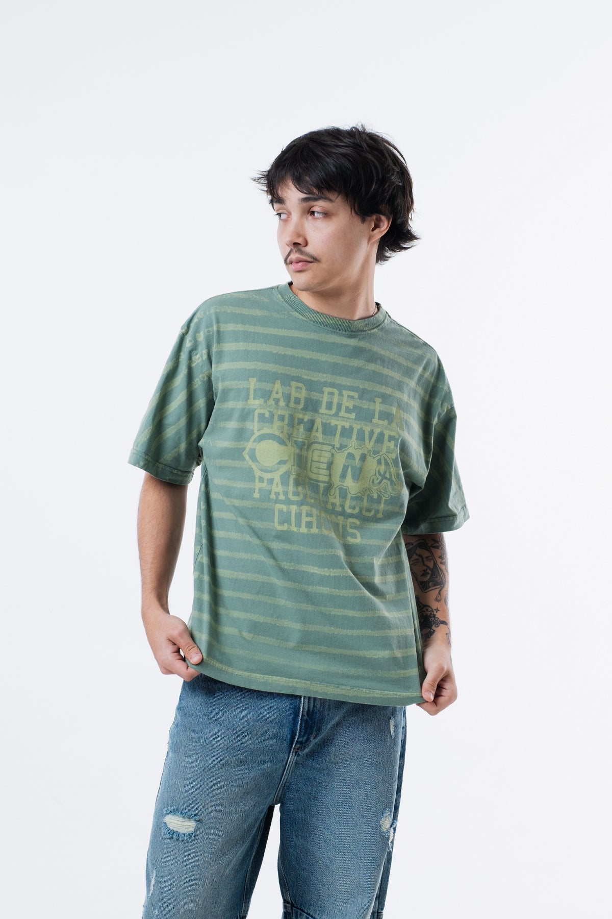 Modelo veste a Circus Staff Green Classic Tee, enquadramento aproximado do lettering no peito