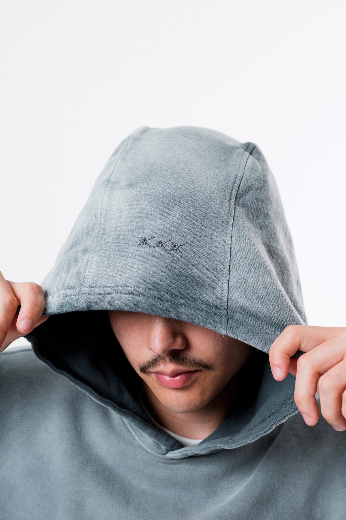 Modelo com o capuz do Aspalth Hoodie cinza cobrindo parte do rosto