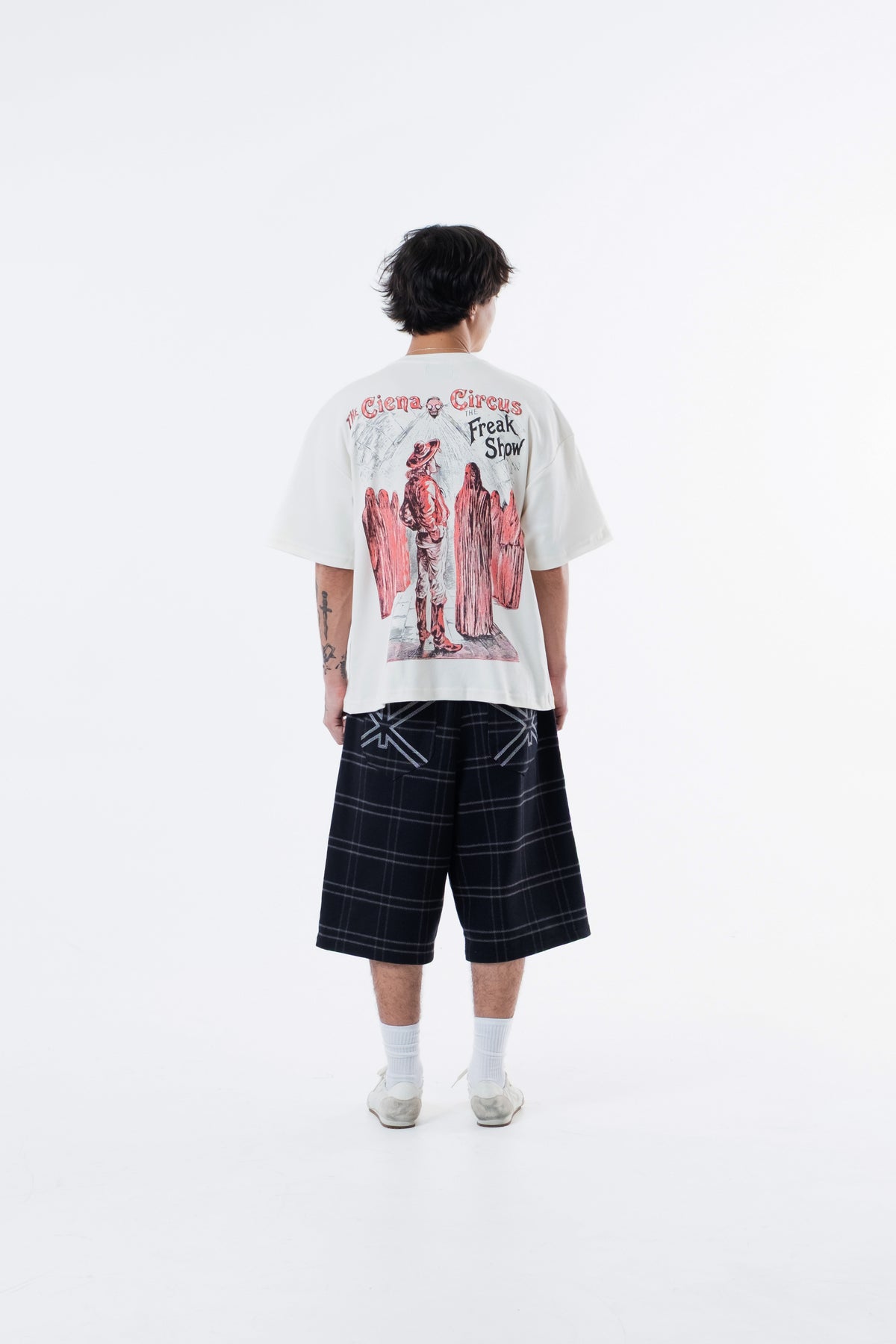 Modelo de costas vestindo a Mystere Heavy Tee off-white, com a arte Circus Freak Show