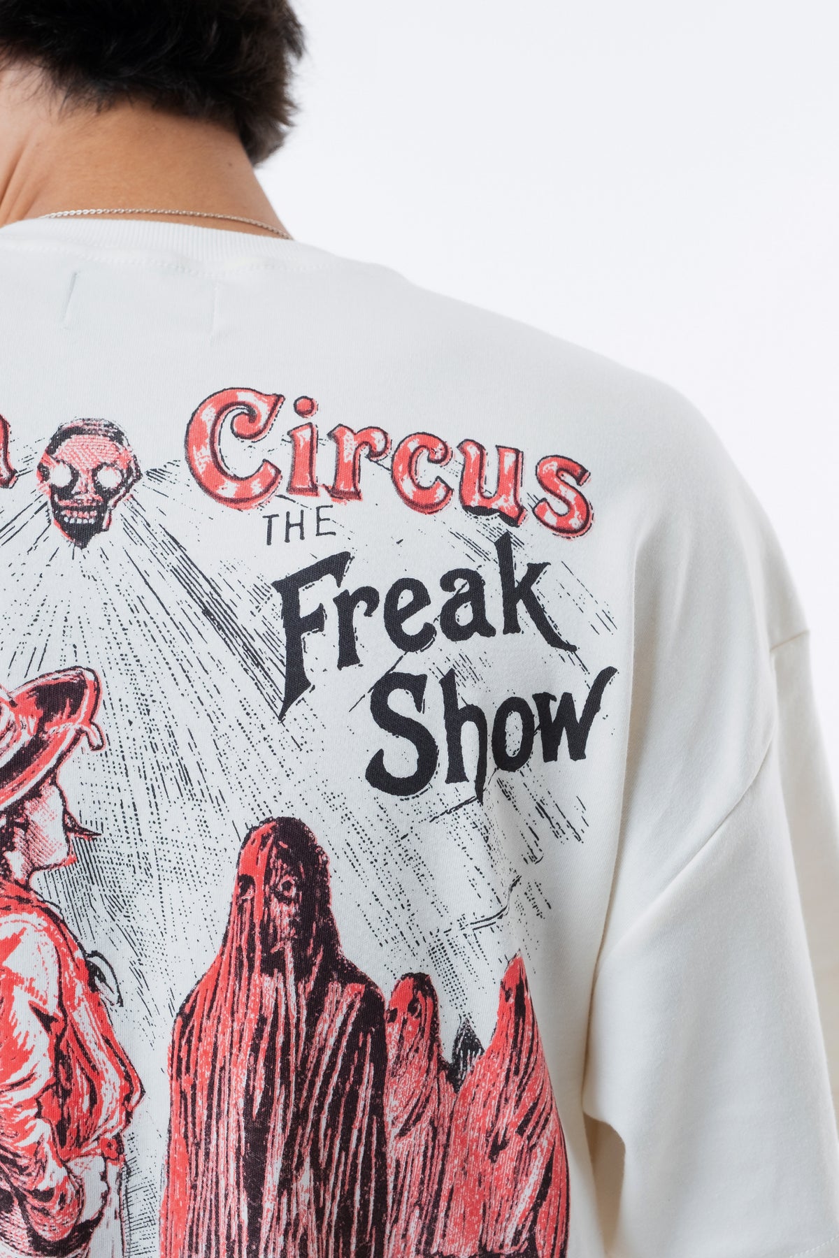 Detalhe aproximado do lettering Freak Show e das figuras encapuzadas em vermelho