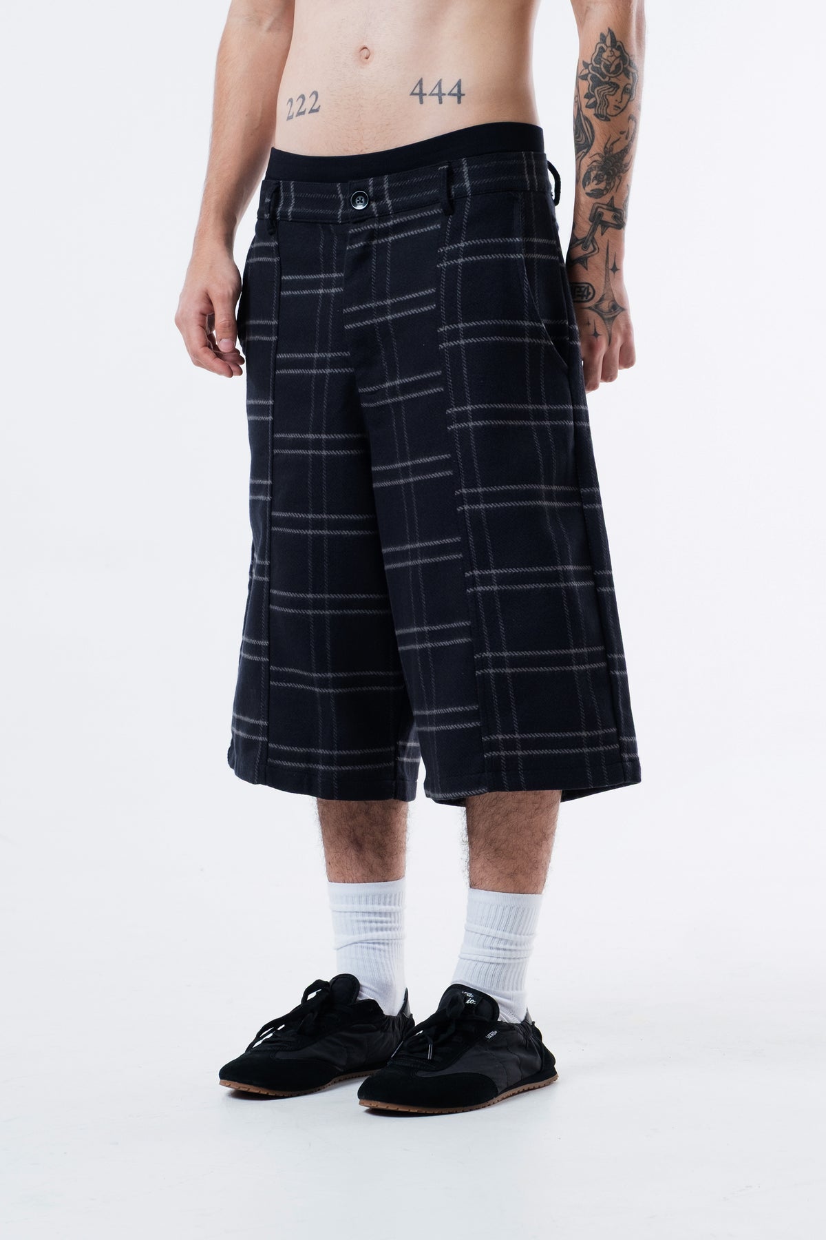Modelo veste a Xadrez Long Shorts preta, vista frontal em outro angulo