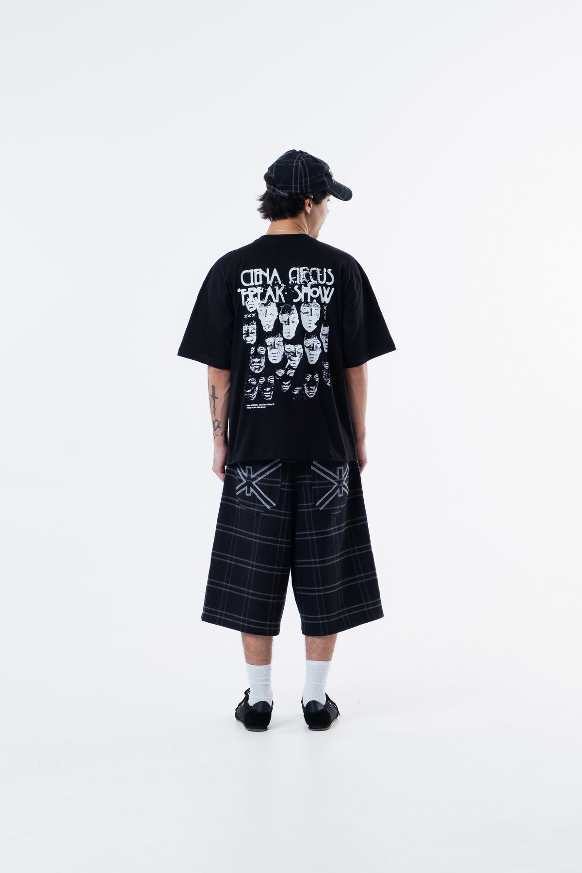 Modelo de costas vestindo a Freak Show Classic Tee preta, com as faces ilustradas nas costas