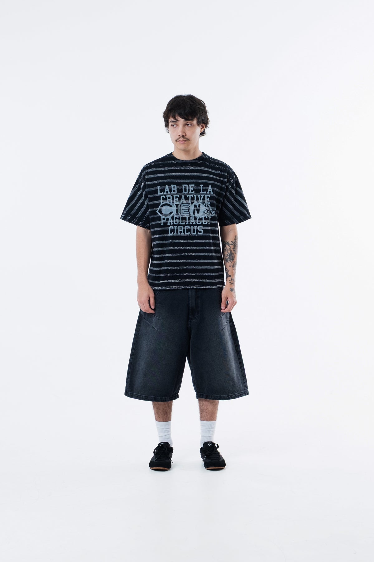 Modelo veste a Circus Staff Black Classic Tee listrada preta, vista frontal de corpo inteiro