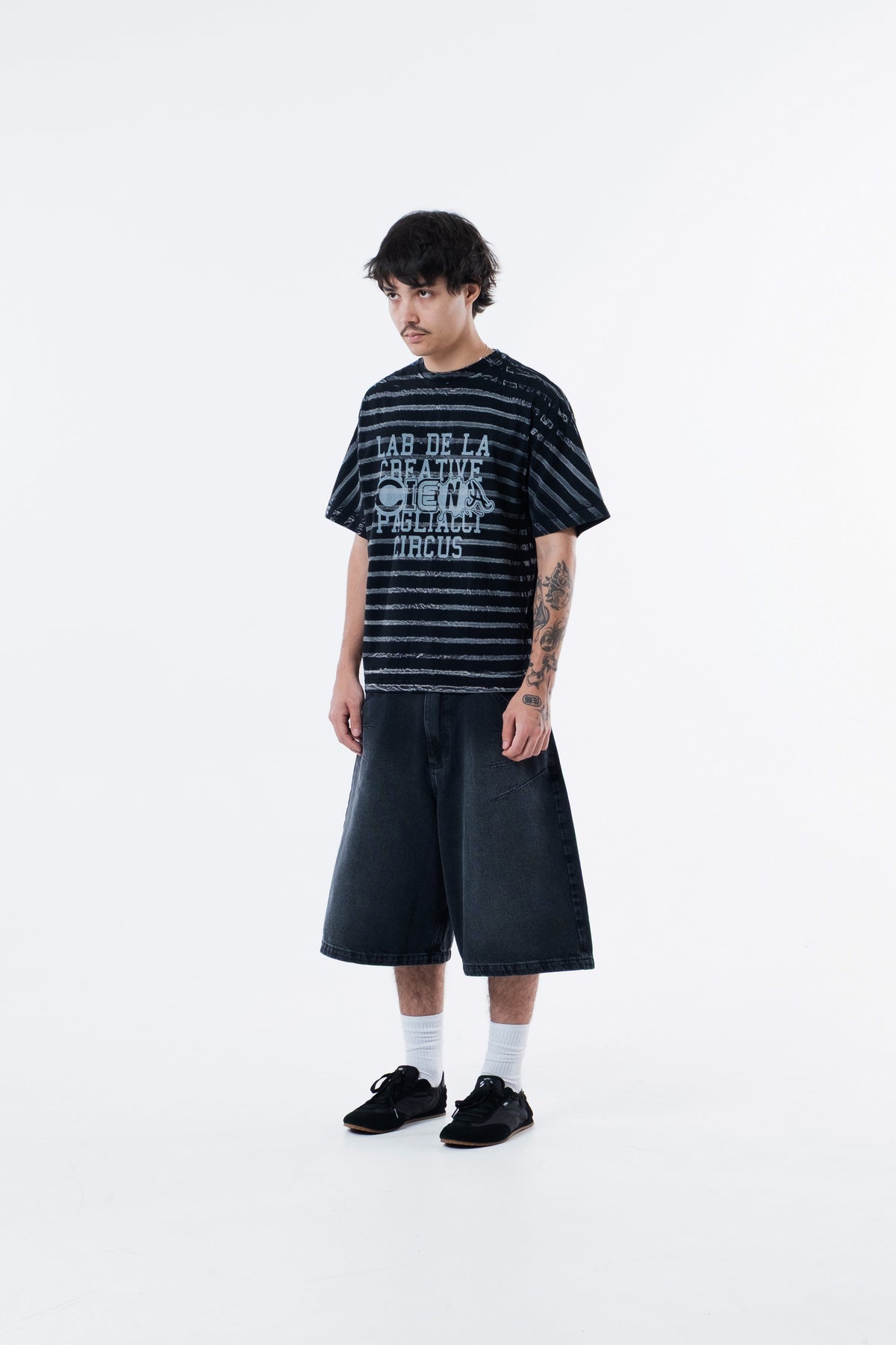 Modelo veste a Circus Staff Black Classic Tee listrada preta, vista frontal em outro angulo