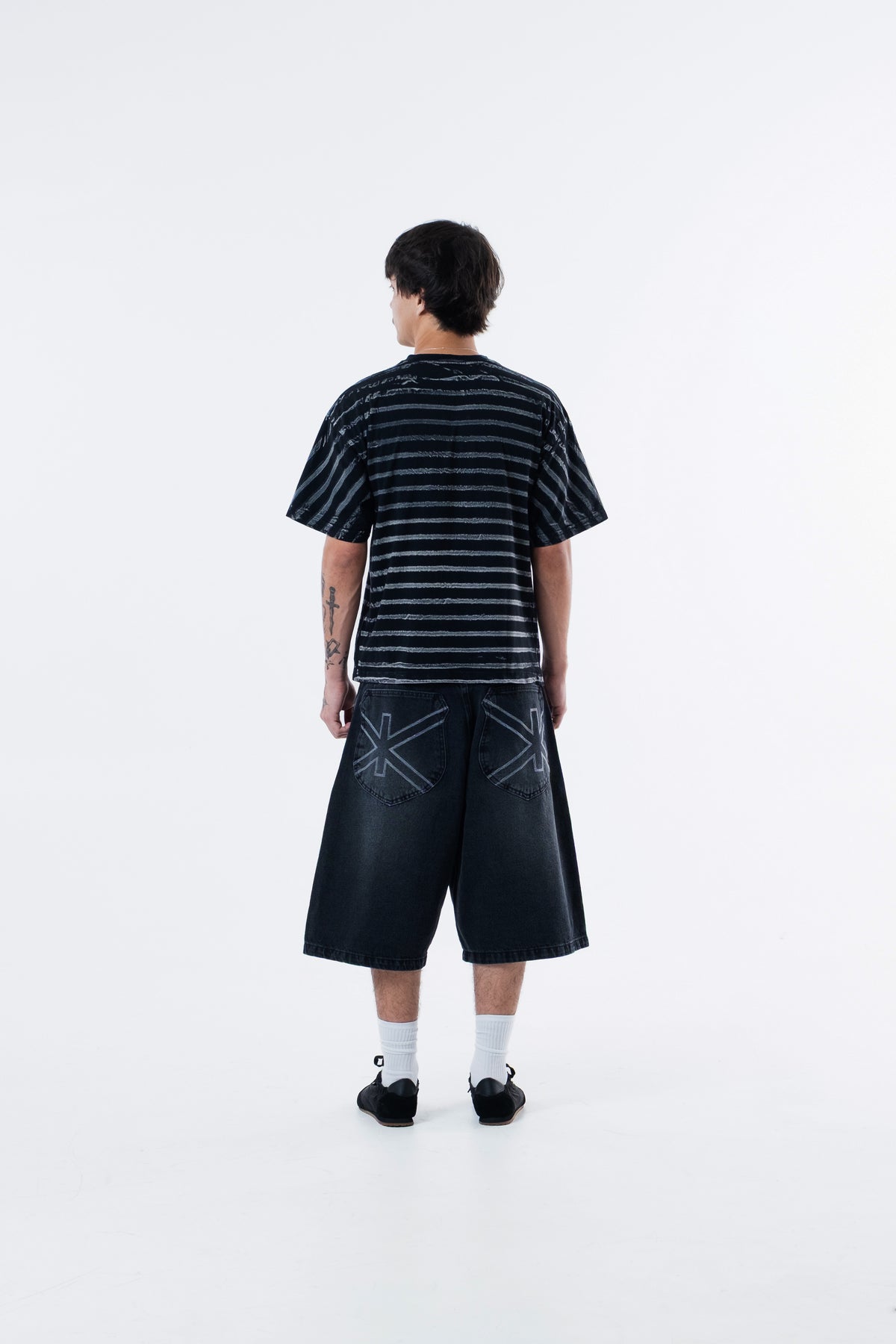 Modelo de costas vestindo a Circus Staff Black Classic Tee listrada preta