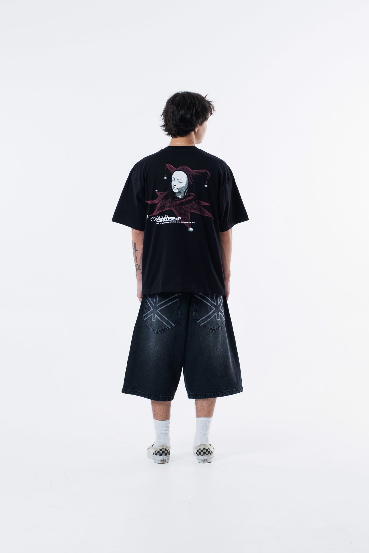 Modelo de costas vestindo a Joker Figure Classic Tee preta, com a figura do bobo da corte