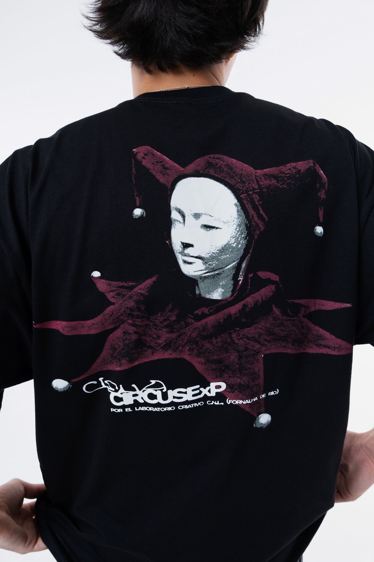 Detalhe da figura do bobo da corte e do lettering Ciena Circus ExP nas costas da camiseta