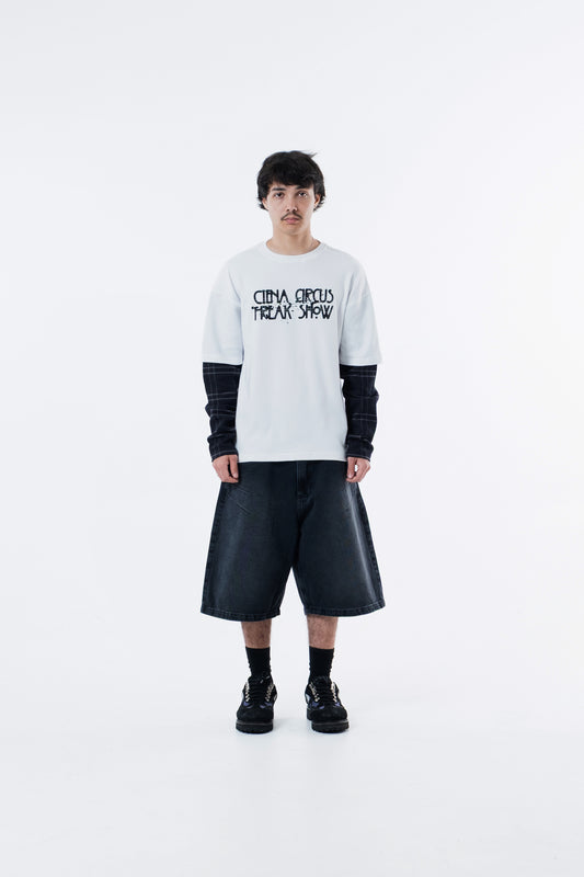 Modelo veste a Freak Show Long Tee off-white com bermuda preta, vista frontal de corpo inteiro
