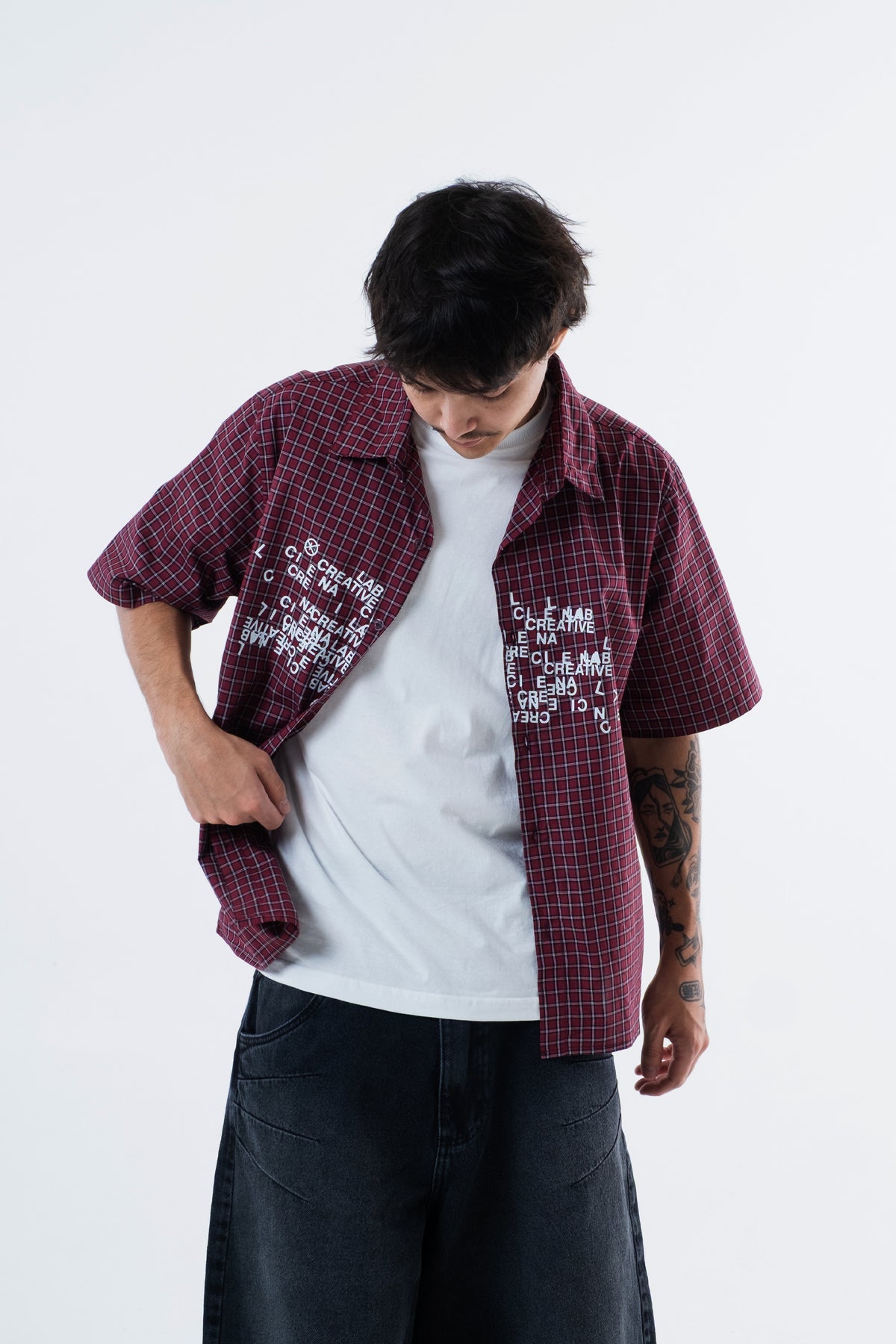 Modelo veste a Xadrez Red Shirt aberta sobre camiseta branca, enquadramento do tronco